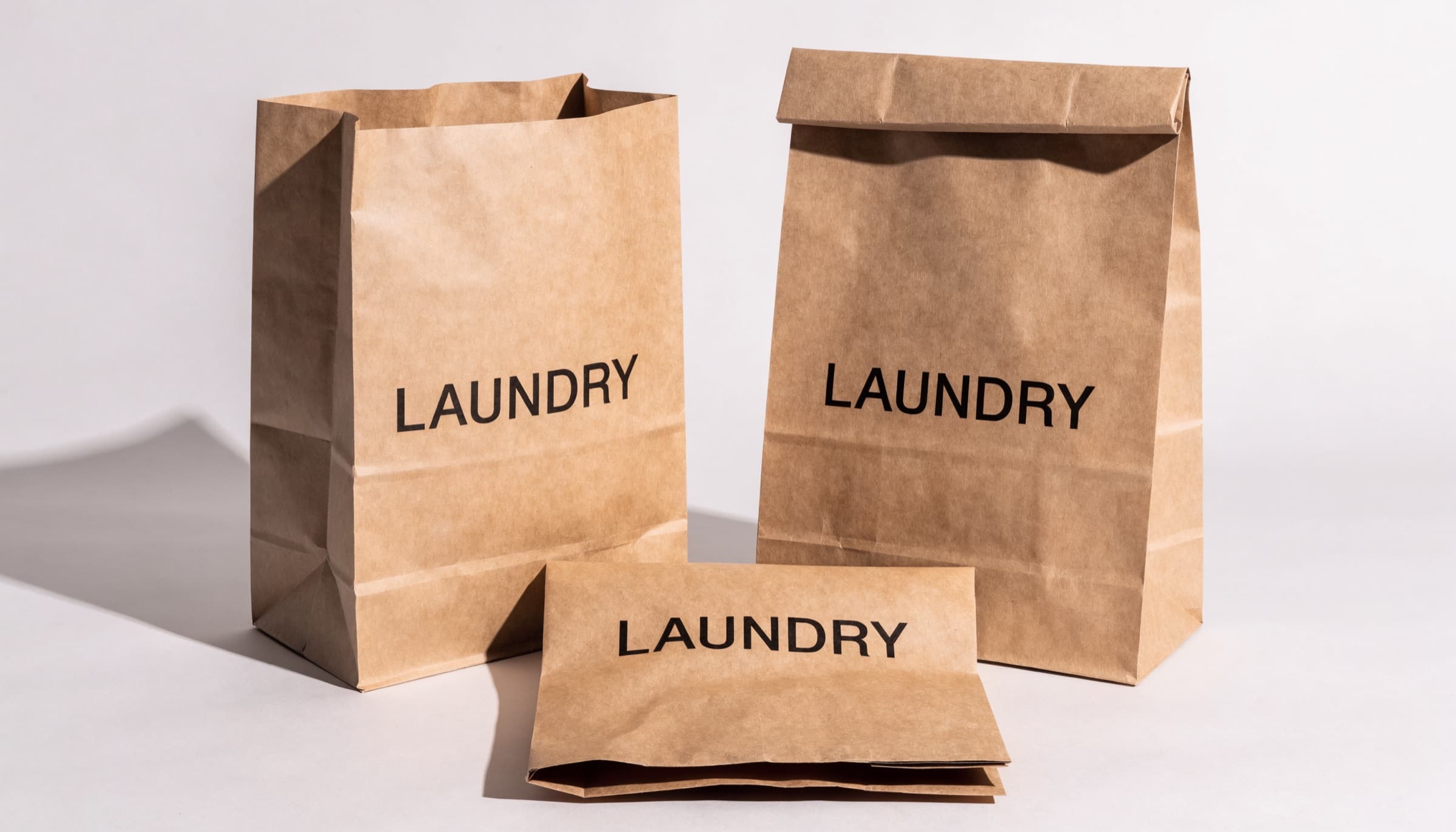 Kraft paper hotel laundry bags printed LAUNDRY, standing open, closed, and folded flat